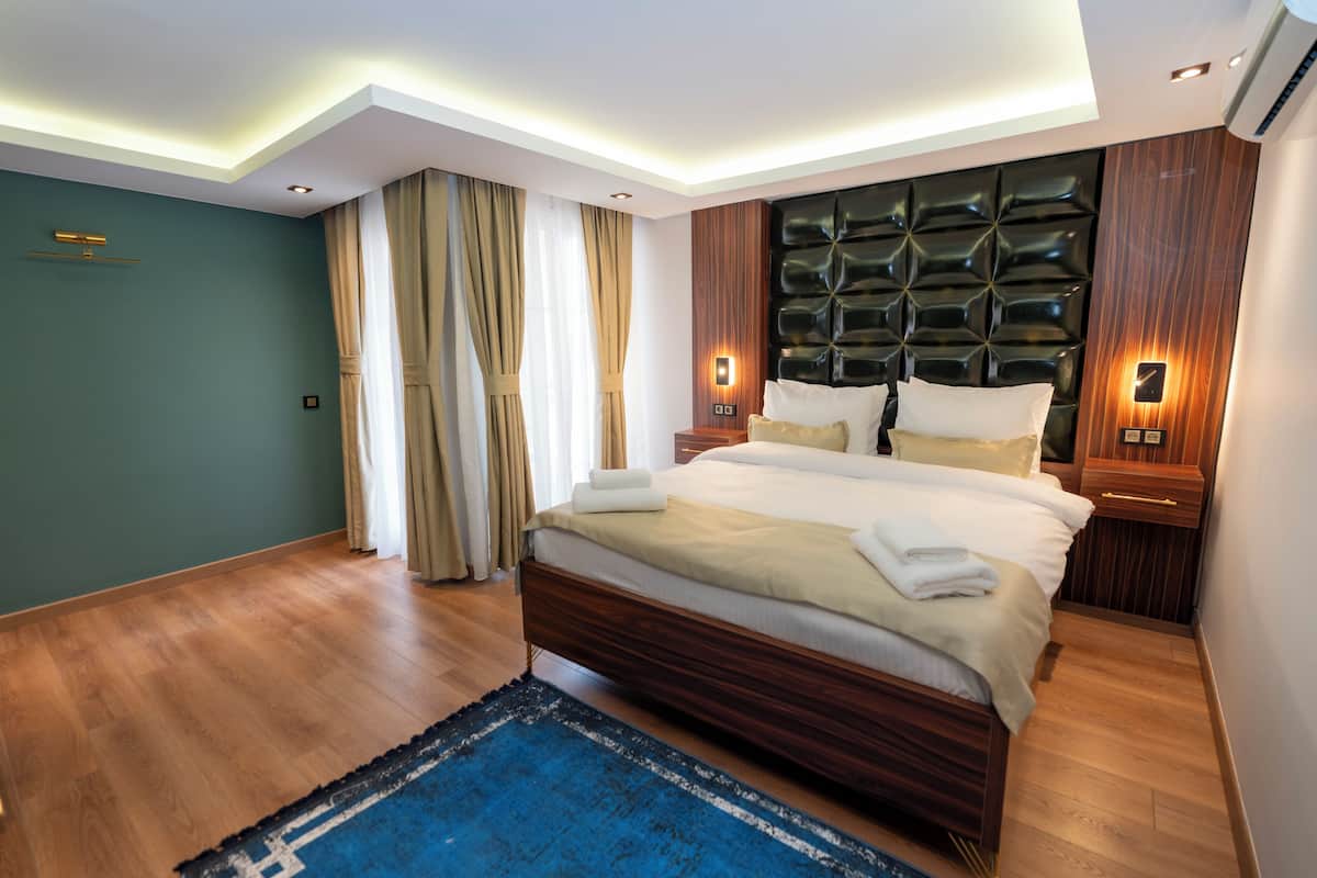A modern bedroom with a wooden bed, a blue rug, and a wall-mounted light fixture.
