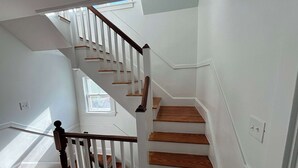 A staircase with white railings and wooden steps, leading to an upper floor. - Downtown Ogunquit Single home, 3 Bedroom (Ogunquit)
