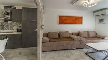 Una sala de estar moderna con un sofá, una mesa de centro y una cocina con armarios y salpicadero de azulejos.