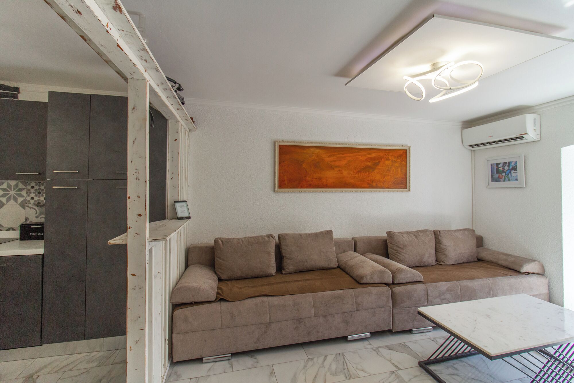 A modern living room with a sofa, a coffee table, and a painting on the wall.