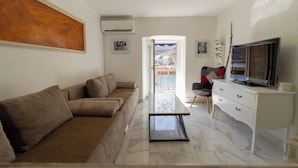 Ein modernes Wohnzimmer mit einer Couch, einem Fernseher und einem Balkon mit Blick.