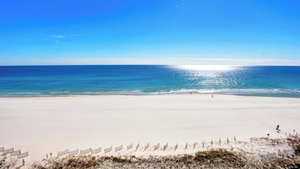 A wide sandy beach with a clear blue sky and calm sea. - Seacrest 905 by Liquid Life (Gulf Shores)