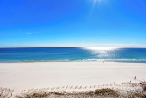 A wide sandy beach with a clear blue sky and calm sea.