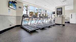 A gym with treadmills, a pool, and large windows with a view of palm trees. - Crystal Tower 807 by Liquid Life (Gulf Shores)