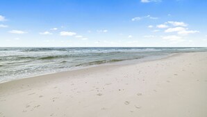 A sandy beach with footprints and a clear blue sky.