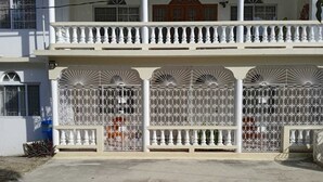 Ein zweistöckiges Gebäude mit weißer Fassade, einem Balkon mit weißen Brüstungen und verzierten Metallgittern.