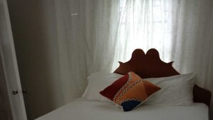 Ein Bett mit weißen Bettwäsche und einem hölzernen Kopfteil.