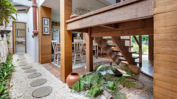 A modern interior with a wooden staircase, a dining area, and a pathway with stepping stones.
