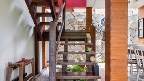 A wooden staircase with a red wall and stone wall in the background.