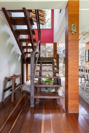 A wooden staircase with a red wall and stone wall in the background.