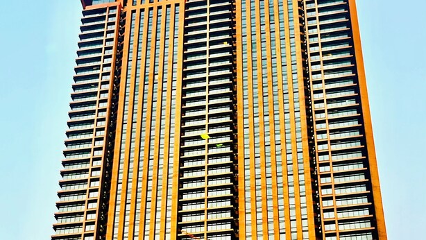 A tall building with a prominent Times Square sign, multiple balconies, and a large glass facade.