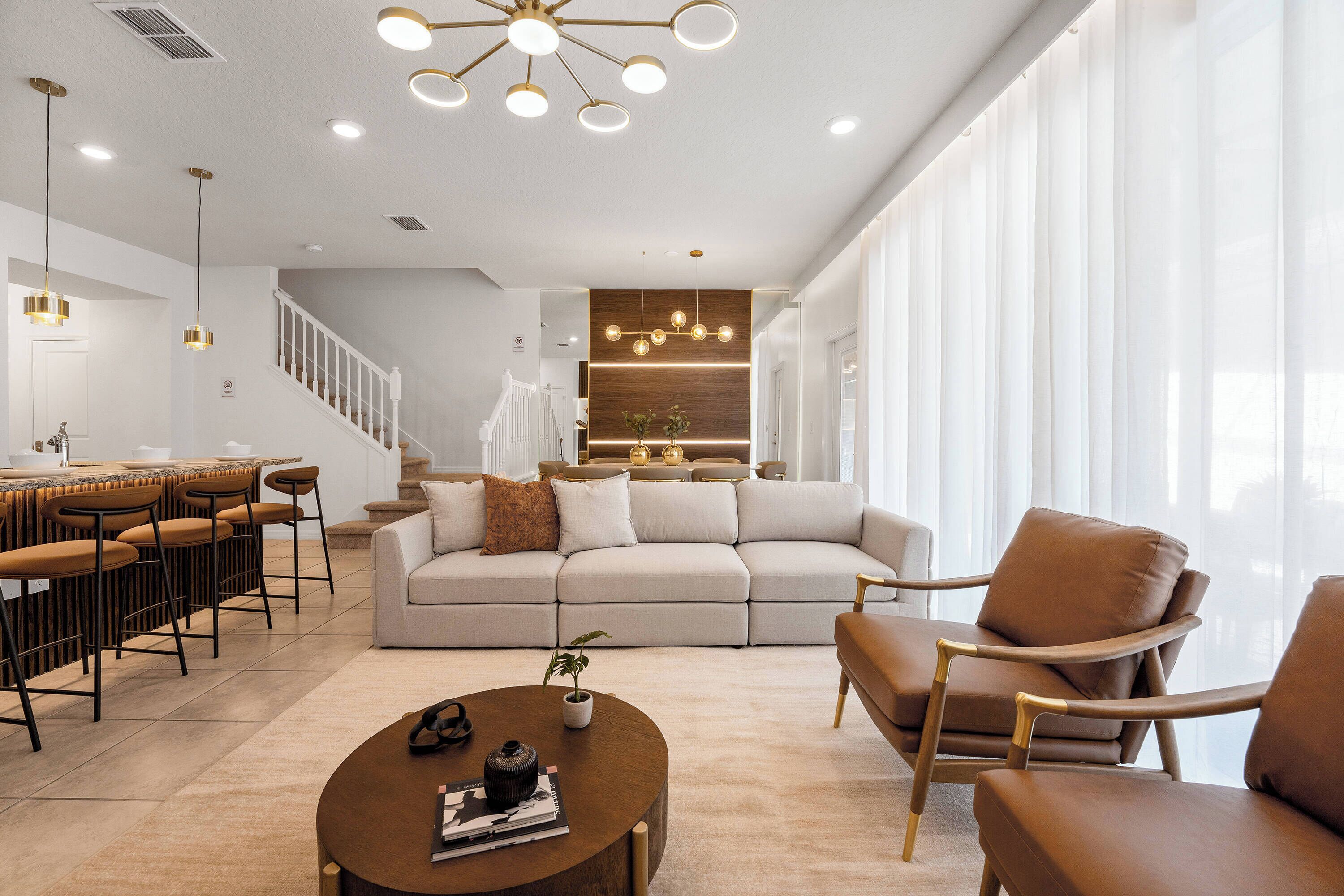 A modern living room with a sofa, armchairs, a coffee table, and a dining area with chairs and a table.