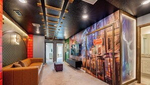 A modern hotel lobby with a curved brown leather sofa, a small purple suitcase, and a vibrant mural on the wall.