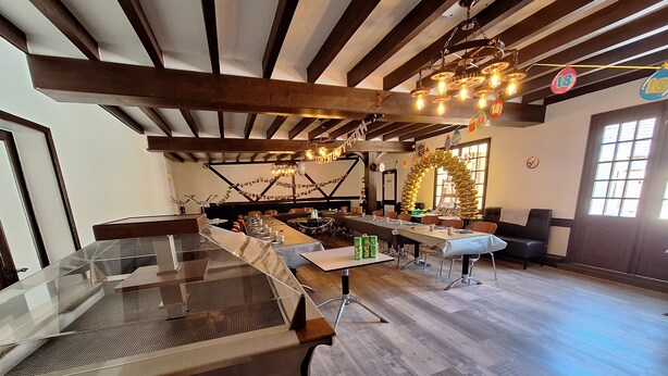 A spacious room with a long dining table, wooden beams on the ceiling, and a chandelier. - Gîte de l'olivier, reception room, parties and ceremonies, events. (Saint-Brisson-sur-Loire)