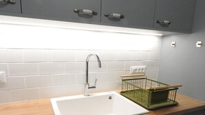 A modern kitchen with a white sink, a green dish rack, and grey cabinets. - Elea Sea View Apartment in Ag. Nikolaos (Agios Nikolaos)