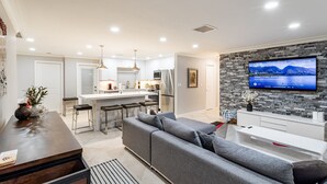 A modern kitchen with white cabinets, a central island, and a dining area.