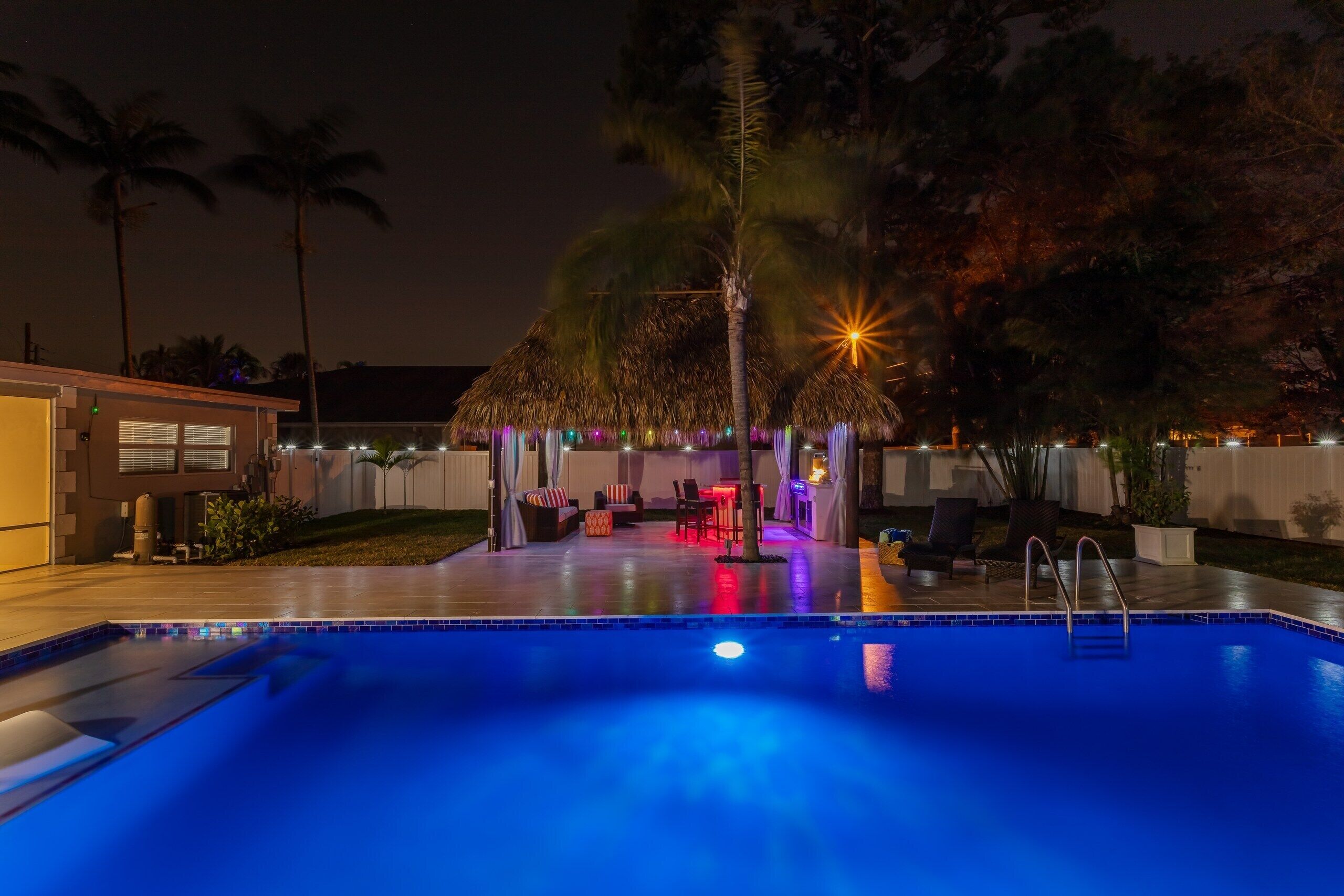 A swimming pool with a thatched-roof structure and lounge area.