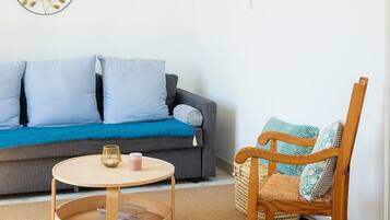 Un salon avec un canapé gris, une table basse ronde en bois, un fauteuil en osier et une décoration murale représentant une carte du monde.