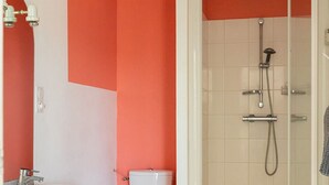 Une salle de bain avec un lavabo, des toilettes et une douche, le tout de couleur blanche.