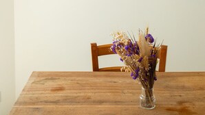 Une table à manger ornée d’un vase de fleurs et trois tableaux encadrés accrochés au mur.