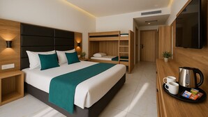 Une chambre d’hôtel moderne équipée d’un grand lit, d’un plus petit lit, d’un bureau avec une bouilloire et des tasses, et d’un téléviseur fixé au mur.