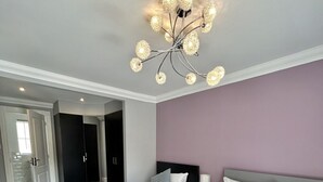 Ein Hotelzimmer mit zwei Betten, einer modernen Kronleuchter und Blick auf den Flur.
