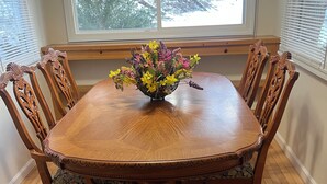 A dining table with a floral centerpiece, surrounded by six chairs with intricate backs. - Charming 1-bedroom house with WiFi, AC in enchanting Burnsville (Burnsville)