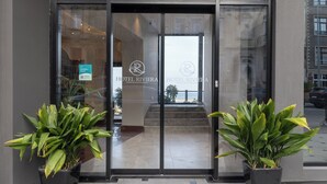 The entrance to Hotel Riviera with glass doors, potted plants, and a visible staircase leading inside.