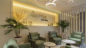 A lobby with green armchairs, a reception desk, and a modern chandelier.