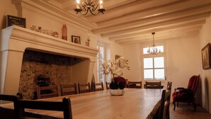 A dining room with a wooden table, chairs, a fireplace, and a chandelier.
