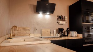 A modern kitchen with a sink, wooden countertop, black cabinets, a microwave, and a built-in oven.