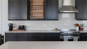 A modern kitchen with dark cabinets, a stainless steel range, and a built-in wine rack. - Historic Rooftop Steps to DT Shops & Dining Unit 3 (Tuscaloosa)