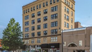 A multi-story building with a flat facade, several ground-level commercial spaces, and a parking area. - Historic Rooftop Steps to DT Shops & Dining Unit 3 (Tuscaloosa)