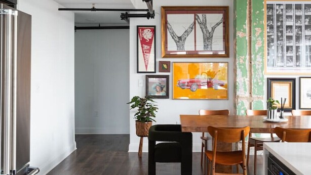 A modern kitchen with dark wood flooring, a wooden dining table, and a built-in oven. - Historic Rooftop Steps to DT Shops & Dining Unit 3 (Tuscaloosa)