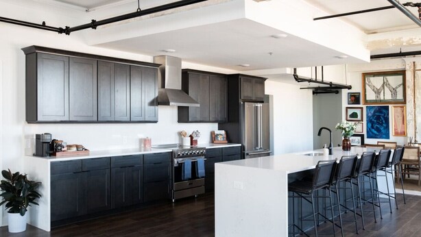 A modern kitchen with dark cabinetry, stainless steel appliances, and a central island with bar stools. - Historic Rooftop Steps to DT Shops & Dining Unit 5 (Tuscaloosa)