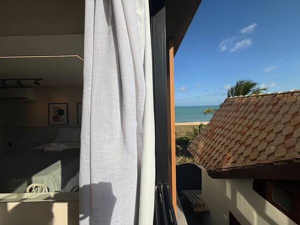 A balcony with a view of the beach and ocean.