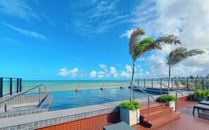 A pool area with a view of the ocean and a city skyline.