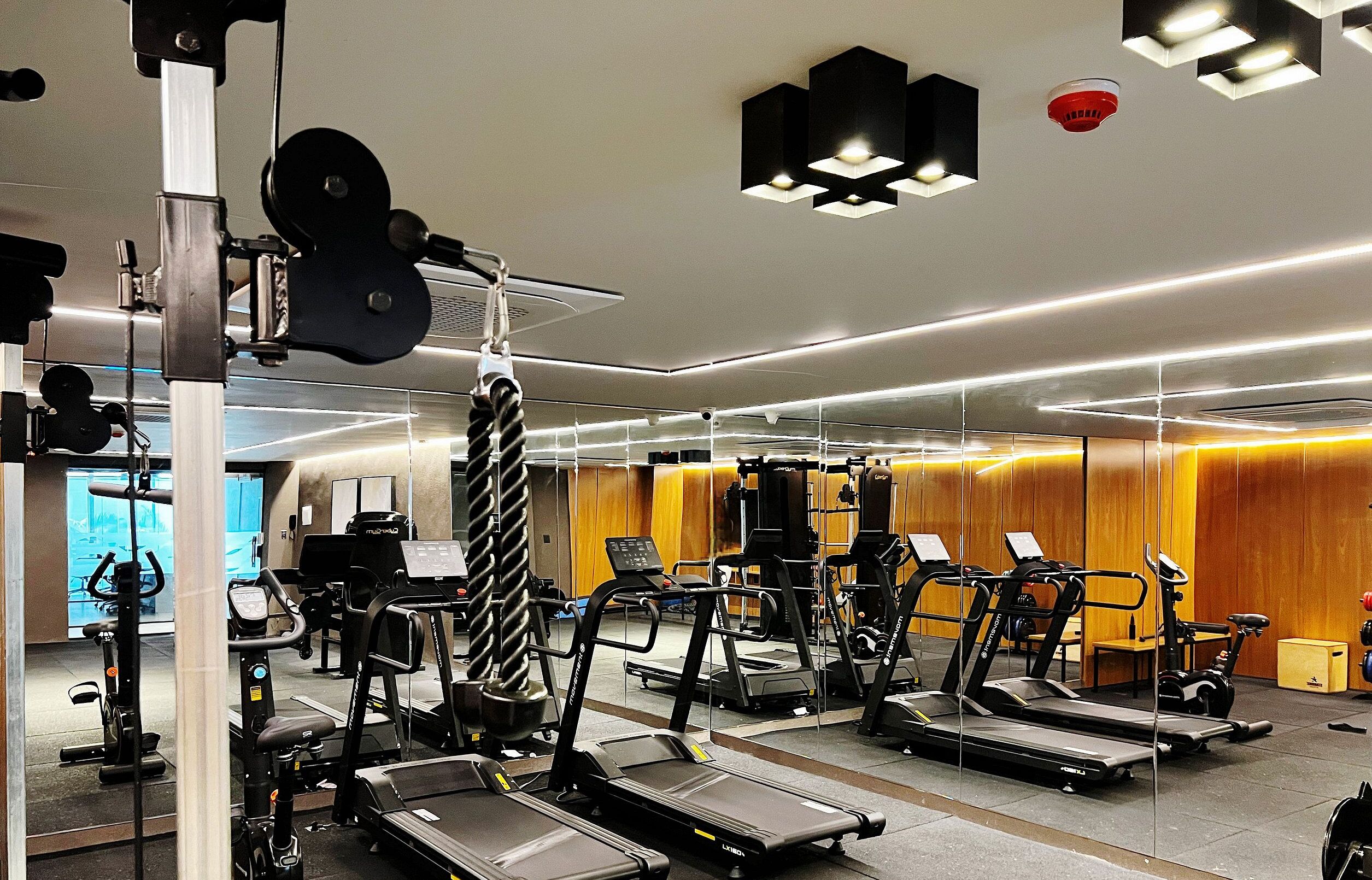 A modern gym with various exercise equipment, including treadmills and weight machines.