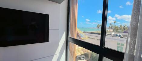 A room with a large window, a flat-screen TV mounted on the wall, and a logo on the window frame.