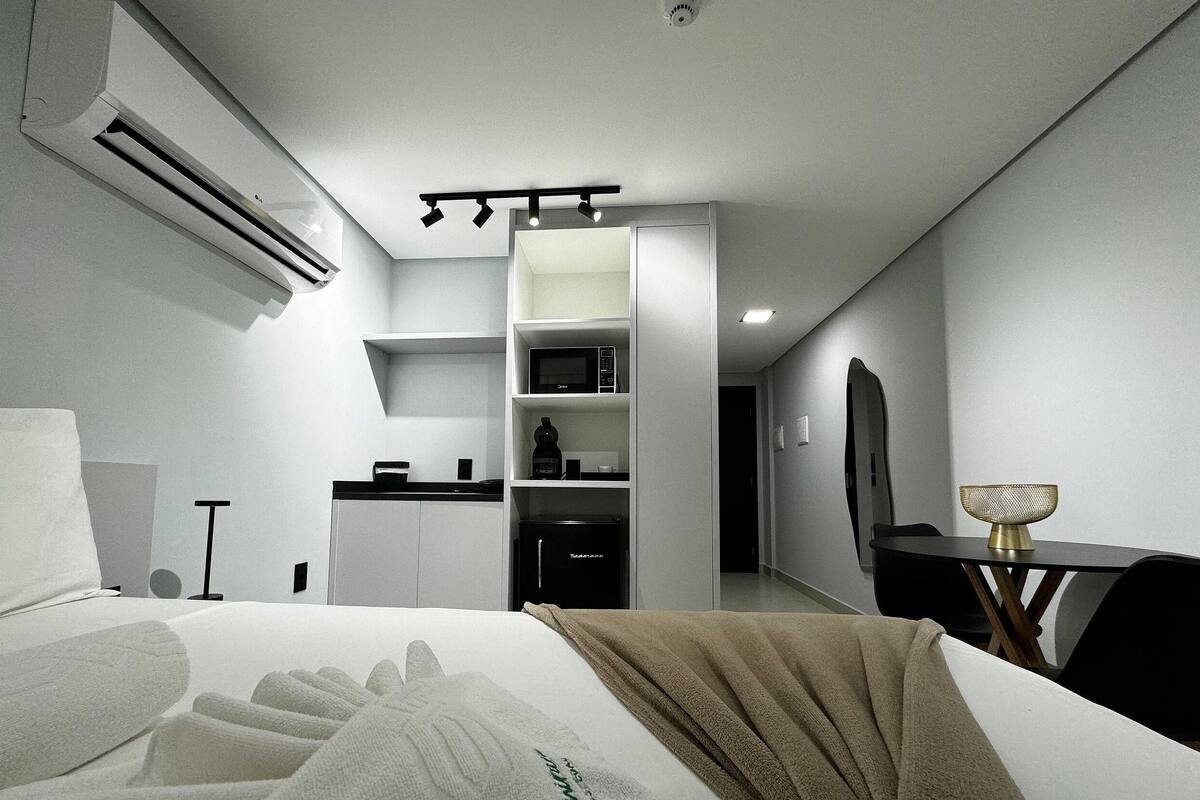 A modern hotel room with a bed, a desk, a microwave, and a minibar.