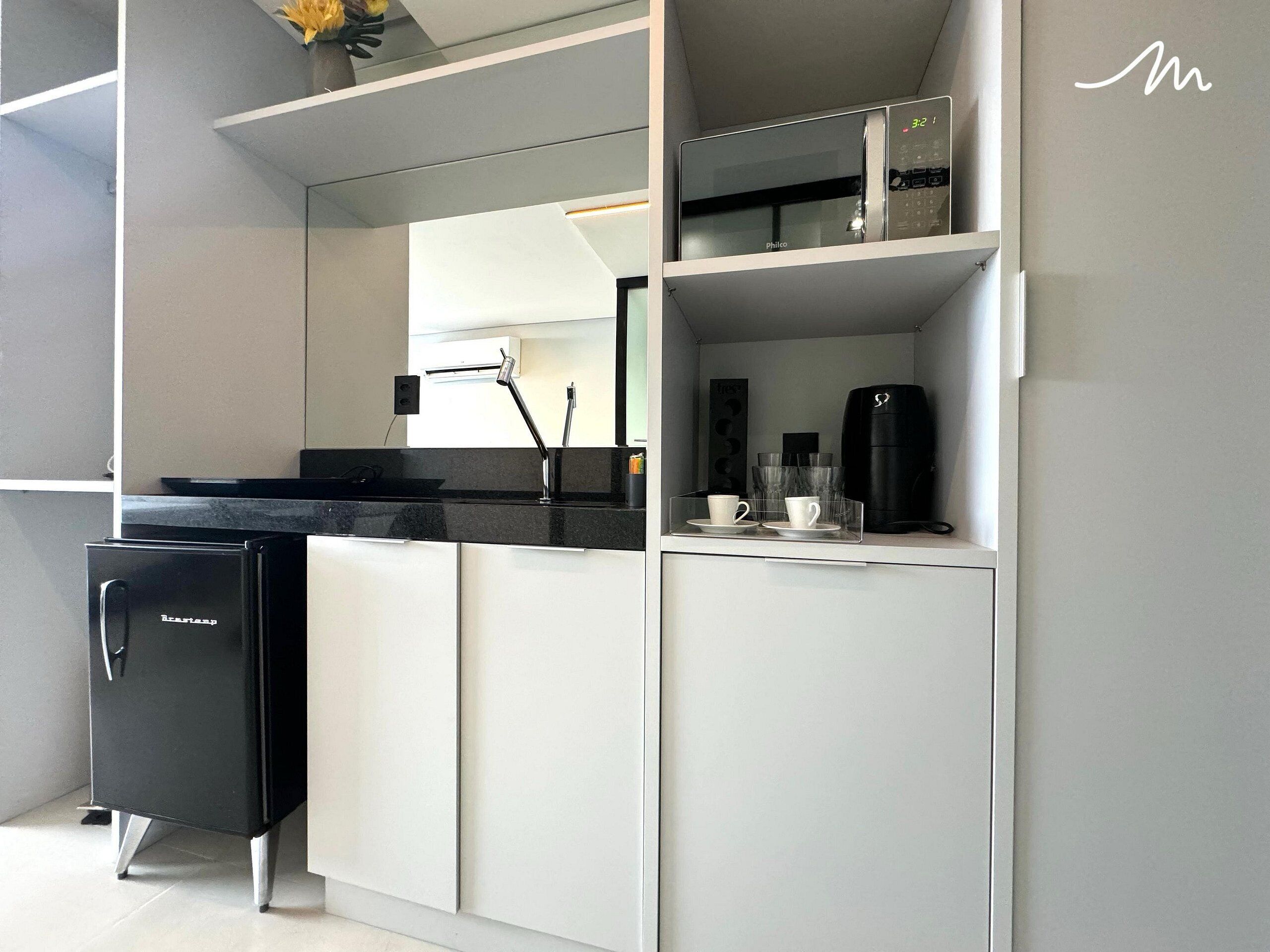 A modern kitchen with a built-in microwave, a coffee maker, and a refrigerator.