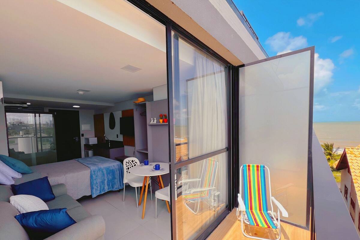 A modern bedroom with a bed, bedside tables, and a glass door leading to a balcony with a chair.