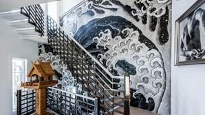 A staircase with a wave pattern mural, a wooden birdhouse, and a framed artwork. - Rosemary Beach Rooftop Heated Pool w/ Carriage House (Rosemary Beach)