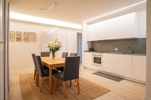 A modern kitchen with white cabinets, a dark countertop, and a built-in oven. - Apartamento Vargas 73. (Santander)
