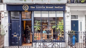 A storefront with a dark blue facade, a sign reading "The Little Bread Peddar," and a bicycle parked in front. - Chic & Cosy Flat, 4-Min Walk to Pimlico Tube. Pet Friendly (London)