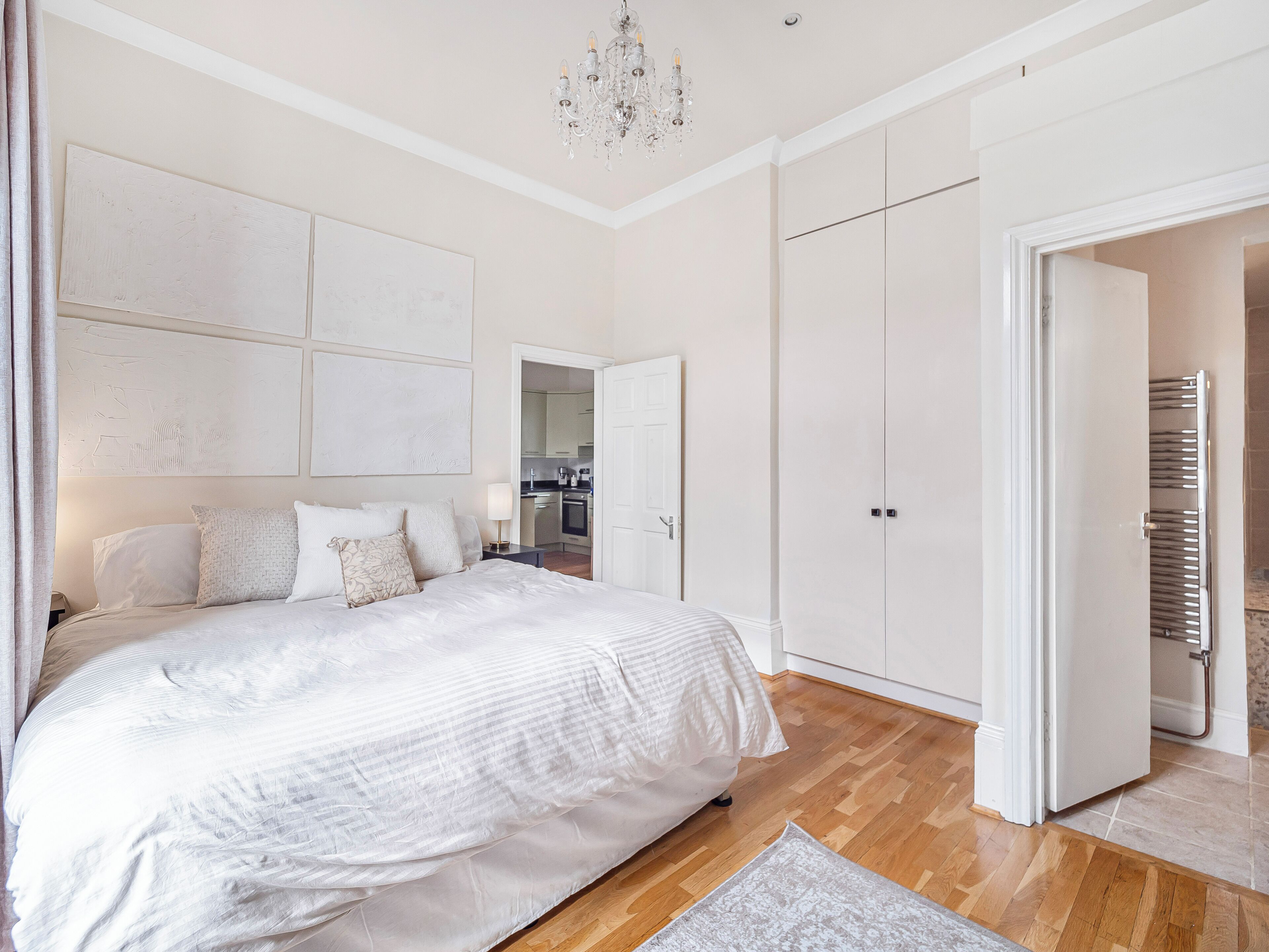 A bedroom with a large bed, a chandelier, and a wardrobe.