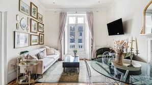 A modern living room with a sofa, coffee table, and glass dining table. - Chic & Cosy Flat, 4-Min Walk to Pimlico Tube. Pet Friendly (London)