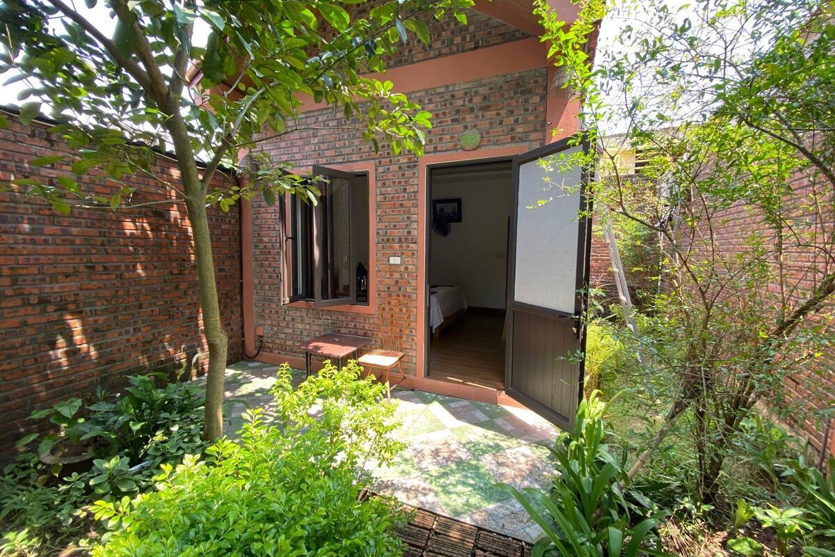 Une maison en briques avec un petit patio, une table en bois et une chaise.