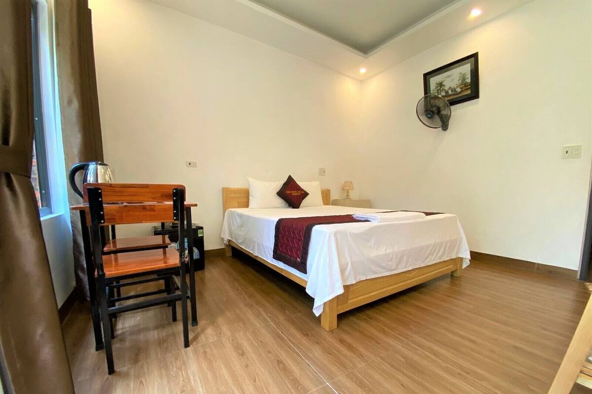 Une chambre à coucher avec un lit en bois, une chaise, une table de chevet et un tableau accroché au mur.