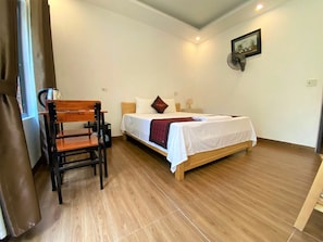 A bedroom with a wooden bed, a chair, a bedside table, and a picture on the wall. - Nam Nhung Tam Coc Homestay (Nam Hoa Lu)